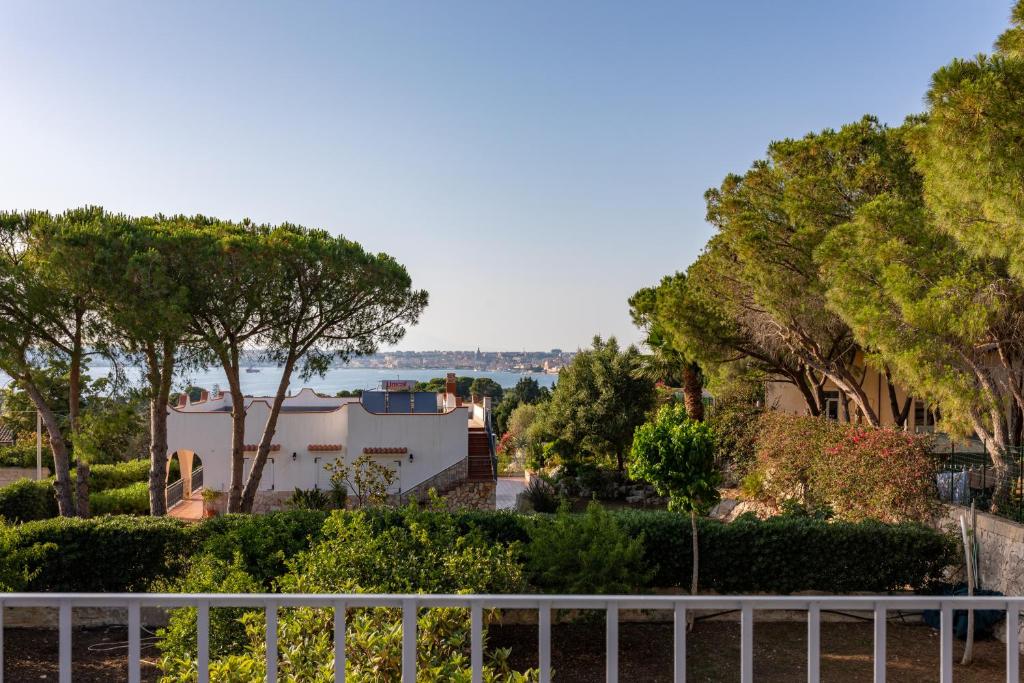 a view of a house with trees and a fence at L'isola di Gianni by Ortigia Apartments in Plemmirio