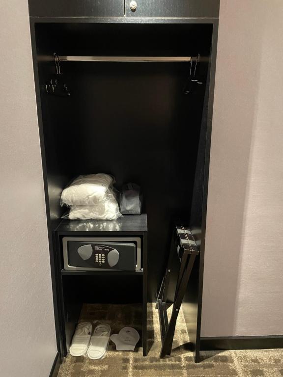 a small closet with a microwave and shoes in it at The Tango Hotel Taipei Nanshi in Taipei
