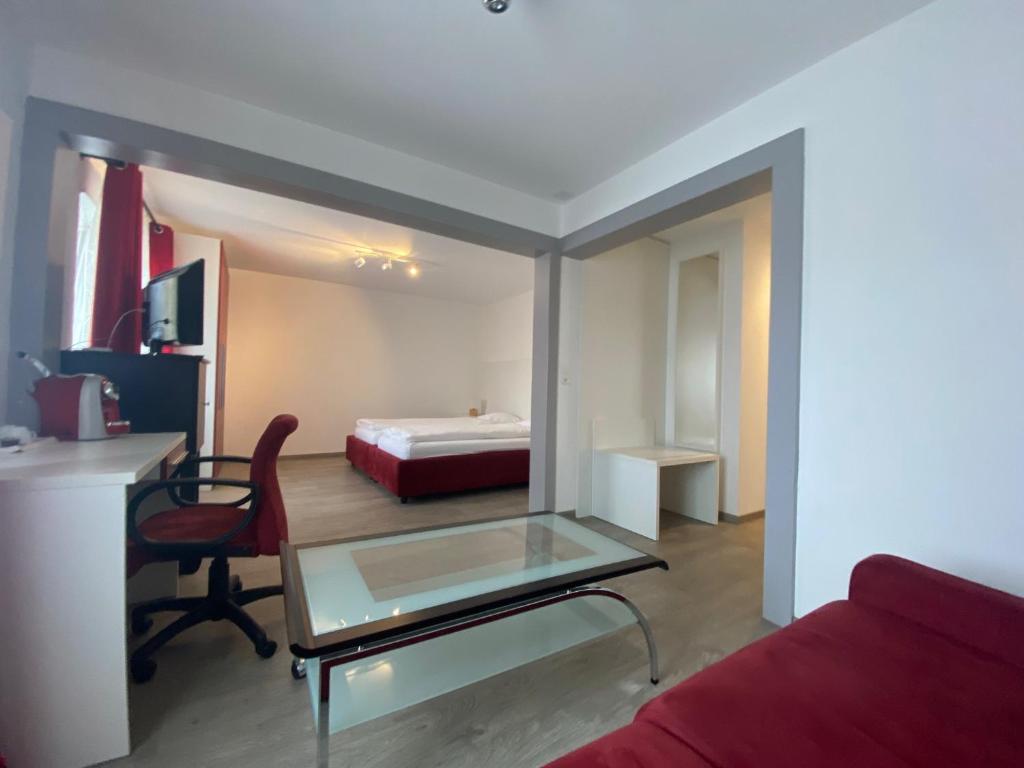 Habitación de hotel con mesa de cristal y cama en Hôtel de la Gare en Saignelégier