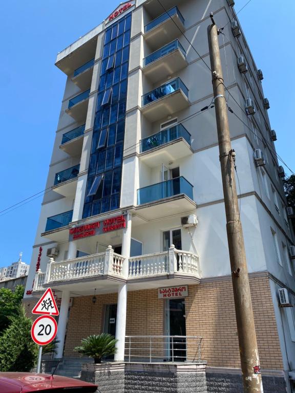 a tall white building with balconies and a street sign at Hotel Garanti in Batumi