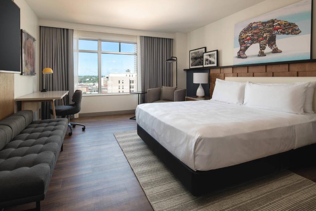 ポートランドにあるThe Bidwell Marriott Portlandの大きなベッドとソファが備わるホテルルームです。