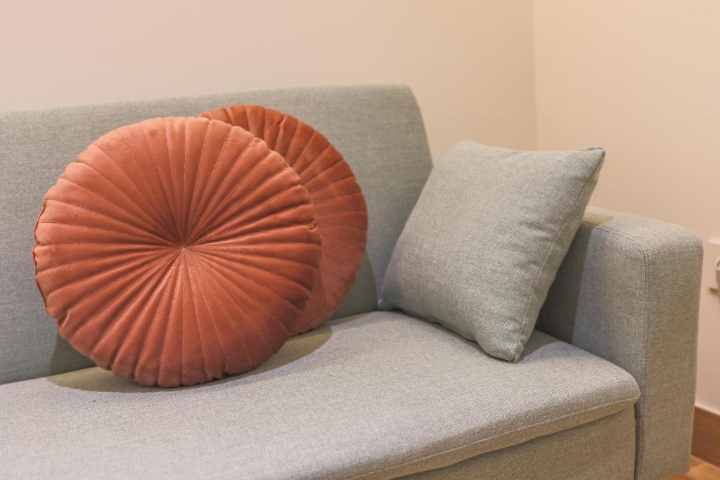 ein orangefarbenes Kissen auf einer grauen Couch mit einem Kissen in der Unterkunft Dorinda Rooms in Alicante