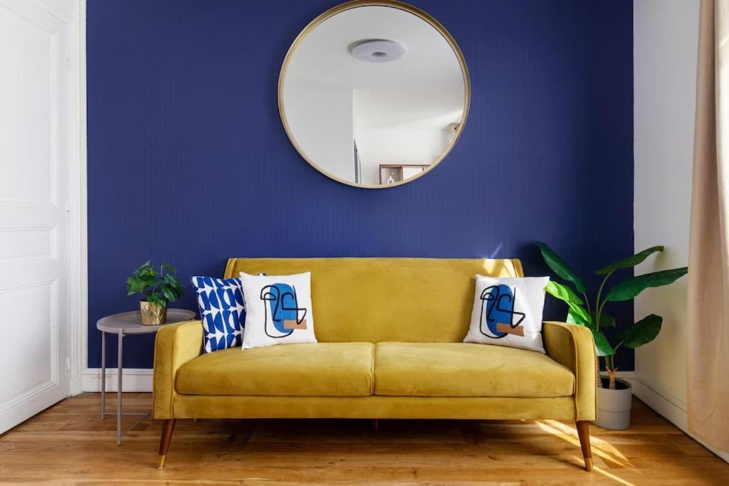 a yellow couch in a living room with a mirror at Chic appartement proche métro in Paris