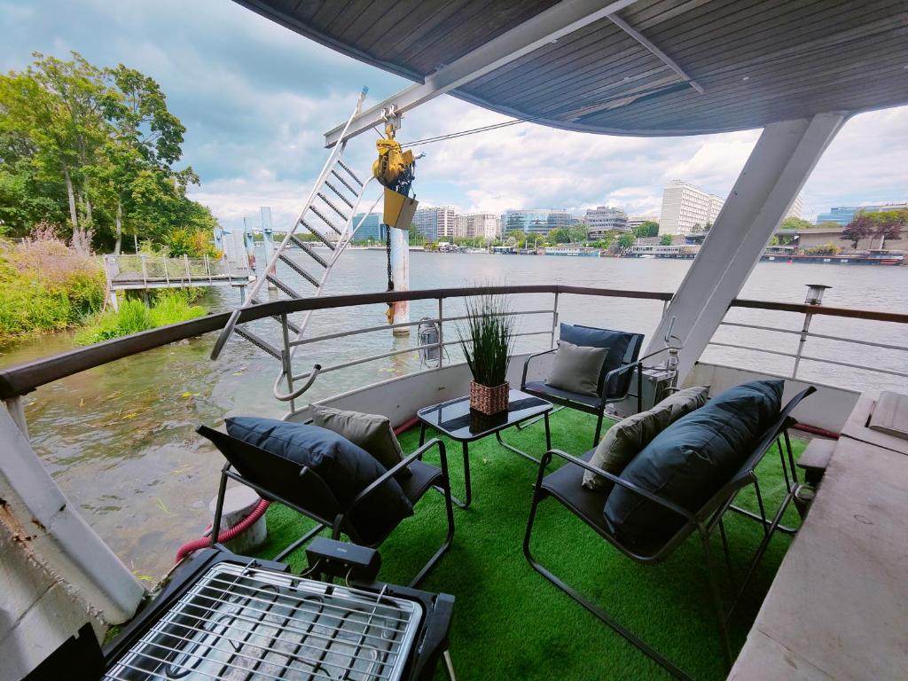 d'un balcon avec des chaises et des tables offrant une vue sur la rivière. dans l'établissement Peniche relaxant, à Sèvres