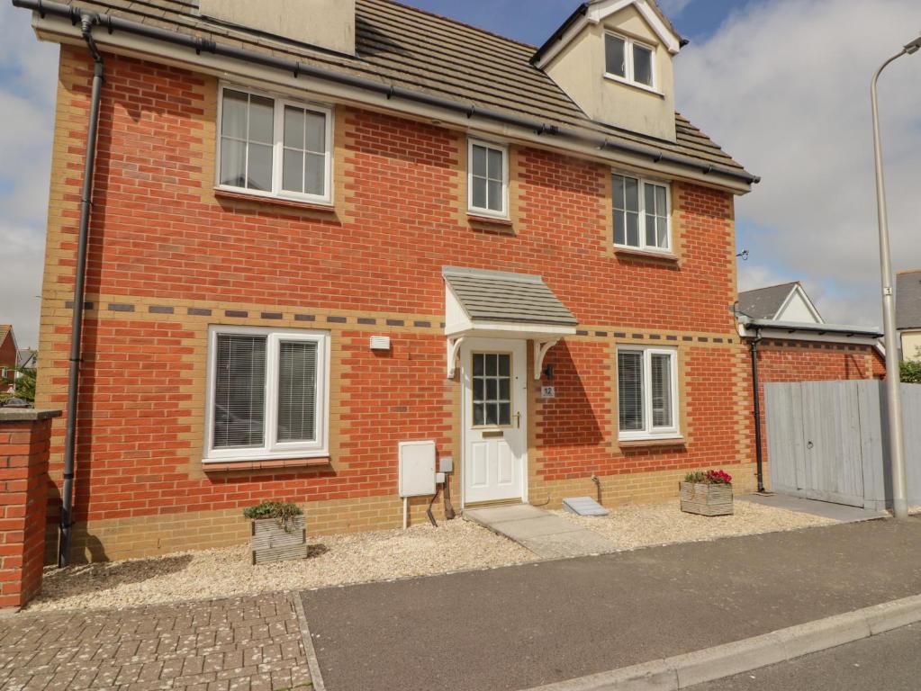 a red brick house with a white door at 12 Clos Yr Wylan in Barry