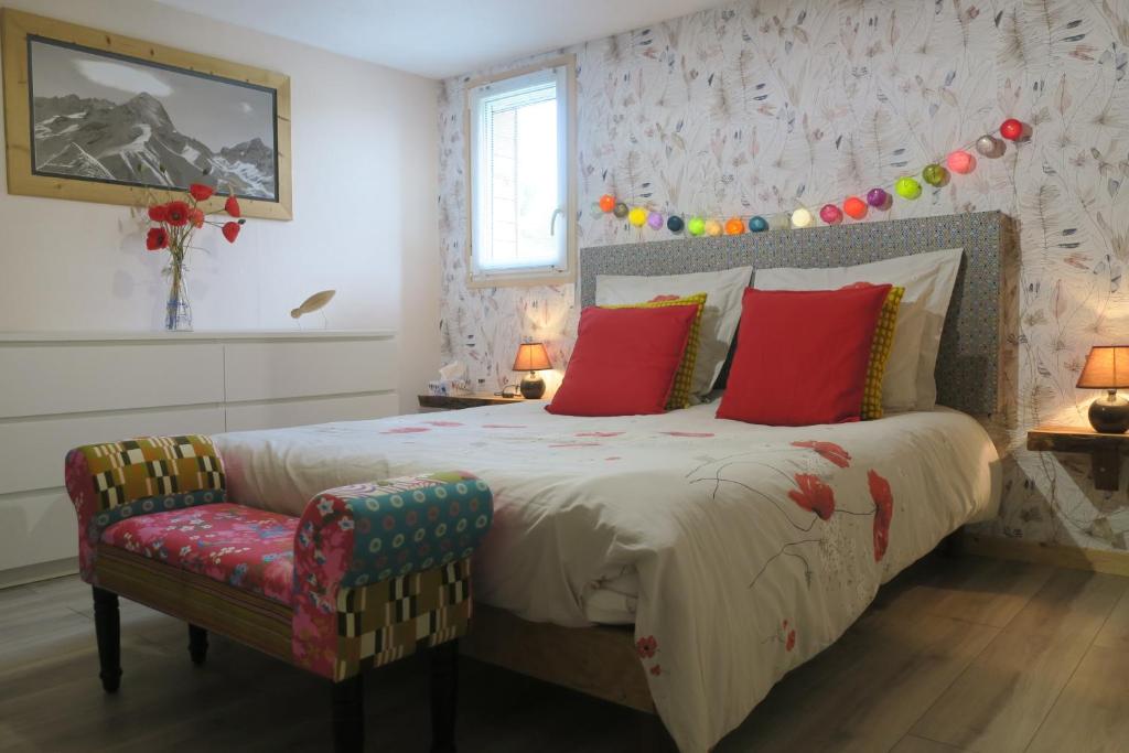 Un dormitorio con una cama con almohadas rojas y una silla en Chambres au grand calme dans maison, en Primarette