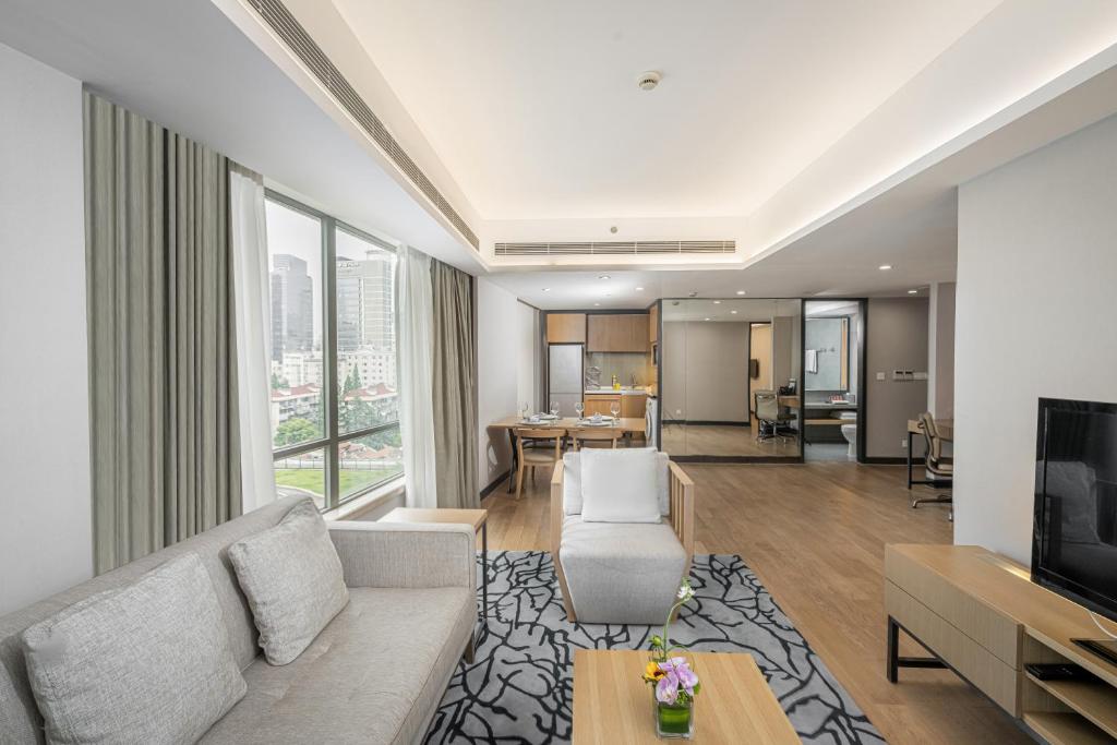 ein Wohnzimmer mit einem Sofa und einem TV in der Unterkunft Riverdale Residence Xintiandi Shanghai in Shanghai