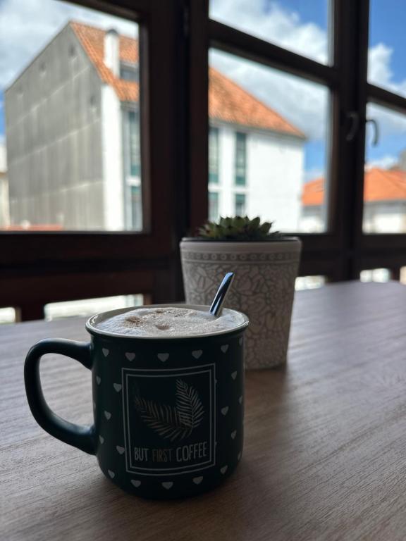 Una taza de café en una mesa con una ventana en O Xaneiro, en Noia