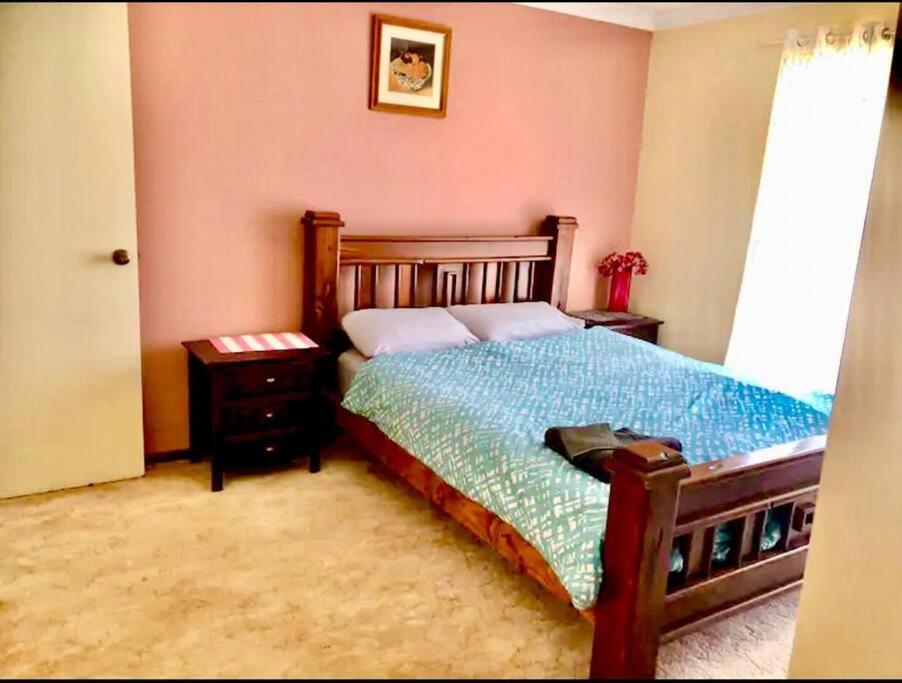 Schlafzimmer mit einem Bett mit einem Holzrahmen und einem Fenster in der Unterkunft Diggers Dealers Accommodation in Kalgoorlie