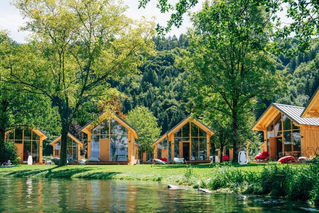 a group of wooden cabins next to a river at Eco Lodges Millstätter See in Döbriach