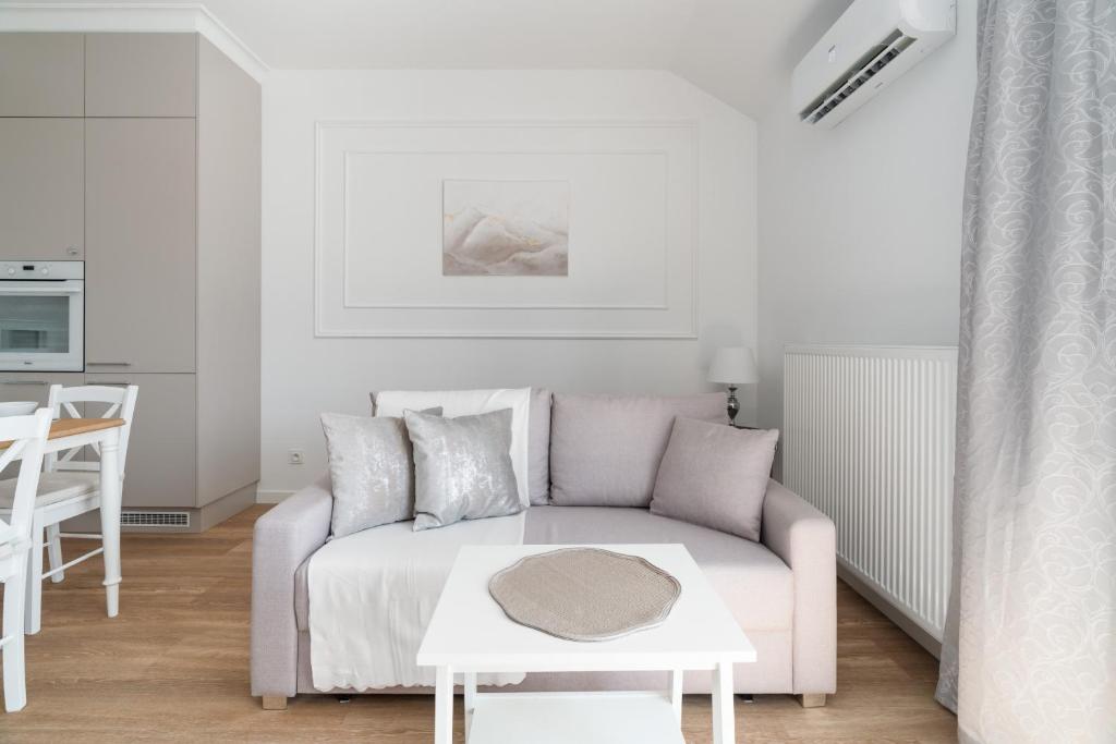 a white living room with a couch and a table at White Elegance Apartment with AC & FREE GARAGE by Renters in Poznań