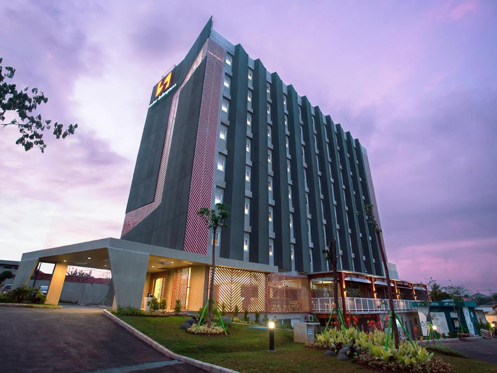 a hotel building with a lit up facade at dusk at Swiss-Belexpress Cilegon in Cilegon