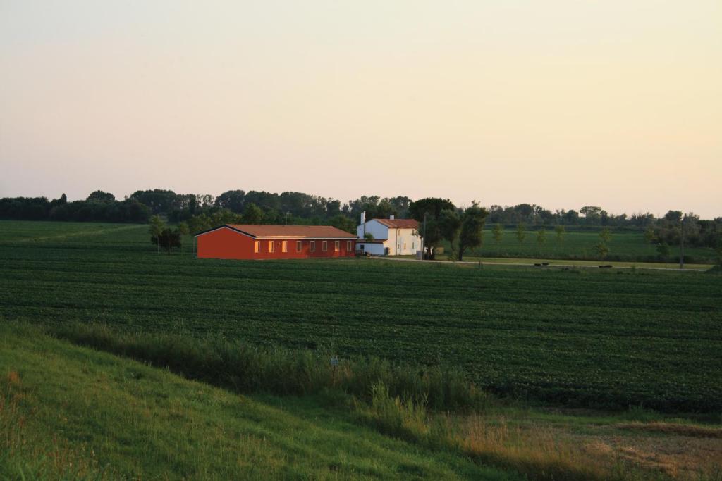 a red barn in the middle of a field at Agriturismo Ca' Pisani in Porto Viro