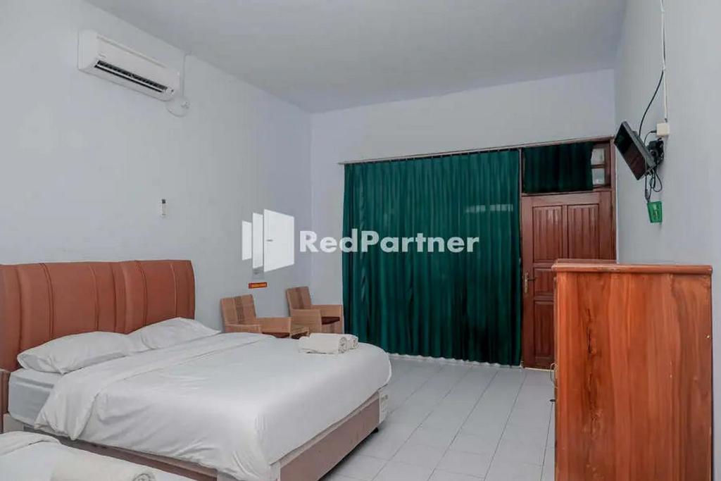 a bedroom with a bed and a green curtain at Pondok Damai Guest House Syariah Mitra RedDoorz in Cirebon