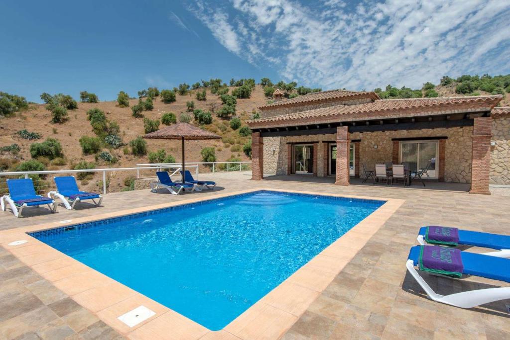 una piscina con sillas y una casa en El Hoyillo by Vintage Travel, en El Gastor