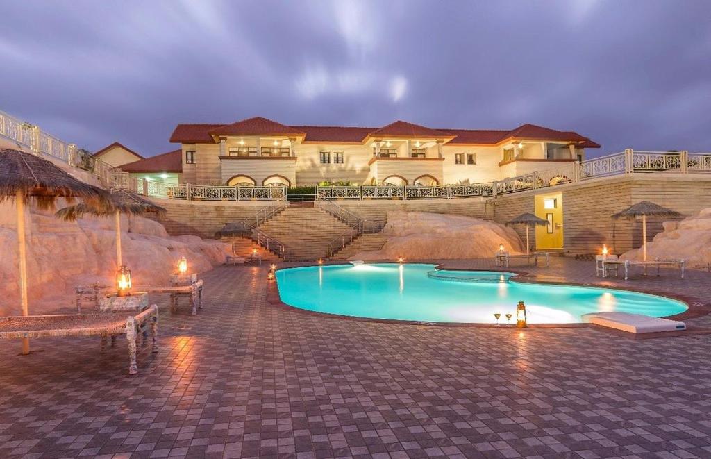 a swimming pool in front of a large house at Regenta Resort Bhuj by Royal Orchid Hotels Limited in Bhuj