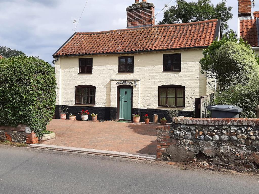 a white house with a green door on a street at Church Cottage in Halesworth