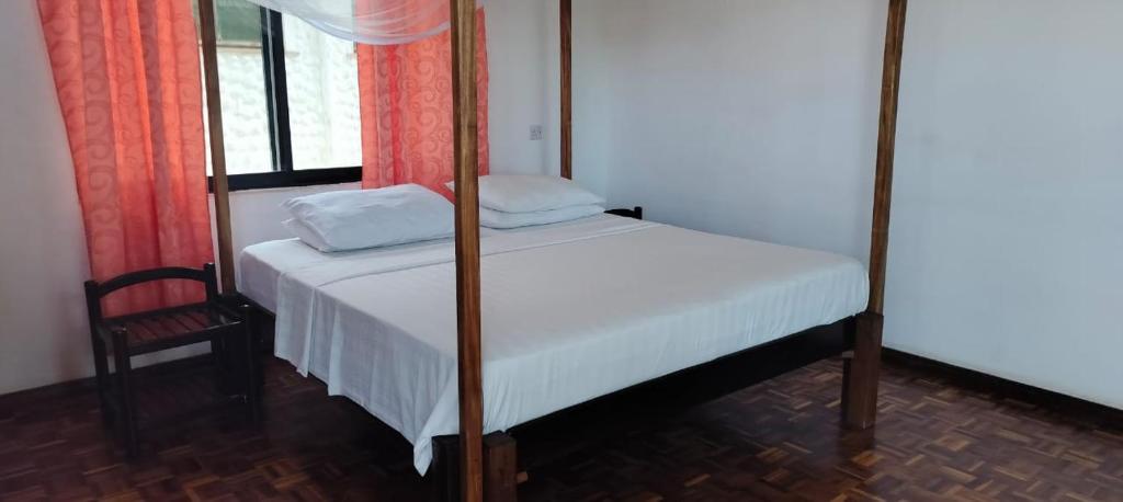 een kleine slaapkamer met een bed en een stoel bij Comfy 1bedroom in Ukunda