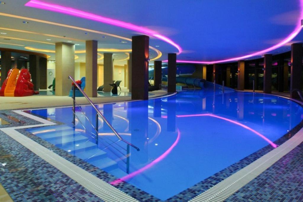 a large swimming pool in a building with purple lighting at Lisi Jar in Jastrzębia Góra