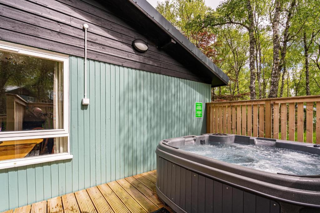 a hot tub on a deck next to a house at Heather Lodge 3 with Hot Tub in Belladrum