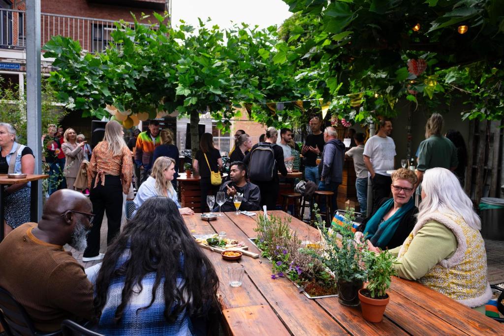 Simplon Hostel في خرونينغن: مجموعة من الناس يجلسون حول طاولة خشبية