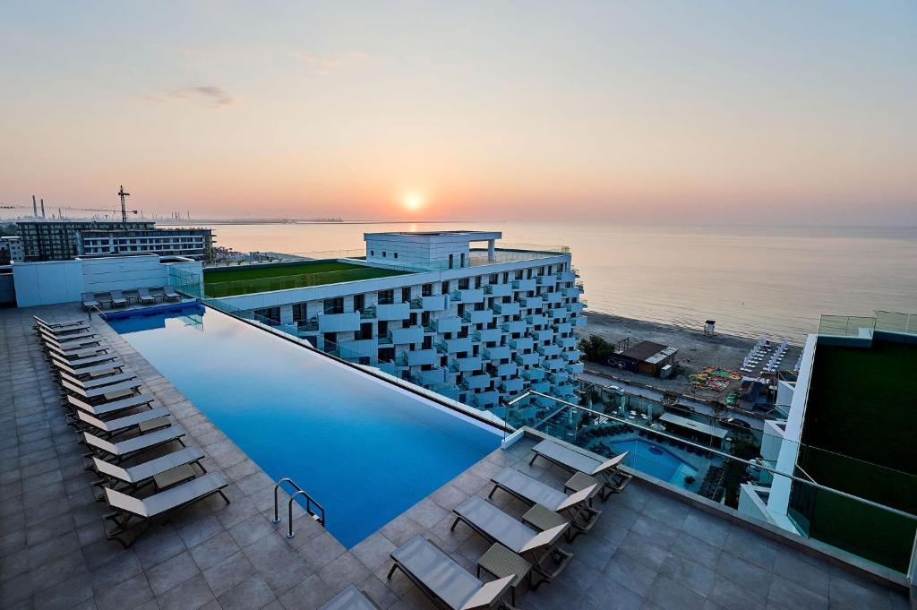 a hotel swimming pool with a view of the ocean at Infinity Breezes Apartment Beach Resort - parking in Mamaia