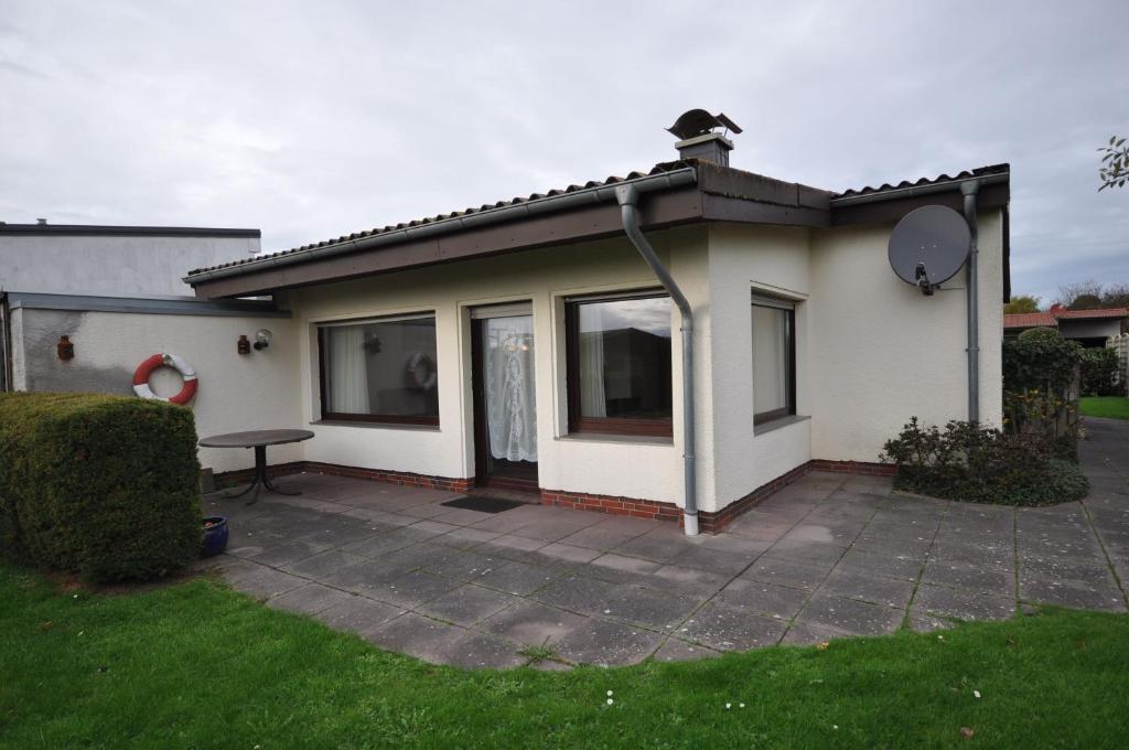 ein kleines Haus mit einer Terrasse im Hof in der Unterkunft Nr 201 - Ferienhaus Am Tief in Neuharlingersiel