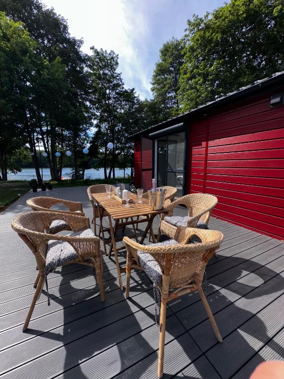 a wooden table and chairs on a patio at Przystanek Krag - kazdy domek ma prywatna balie! Do tego wlasna prywatna plaza, pomost, lodka, kajaki, strefa ciszy, darmowy parking, grille , miejsce na ognisko in Krąg