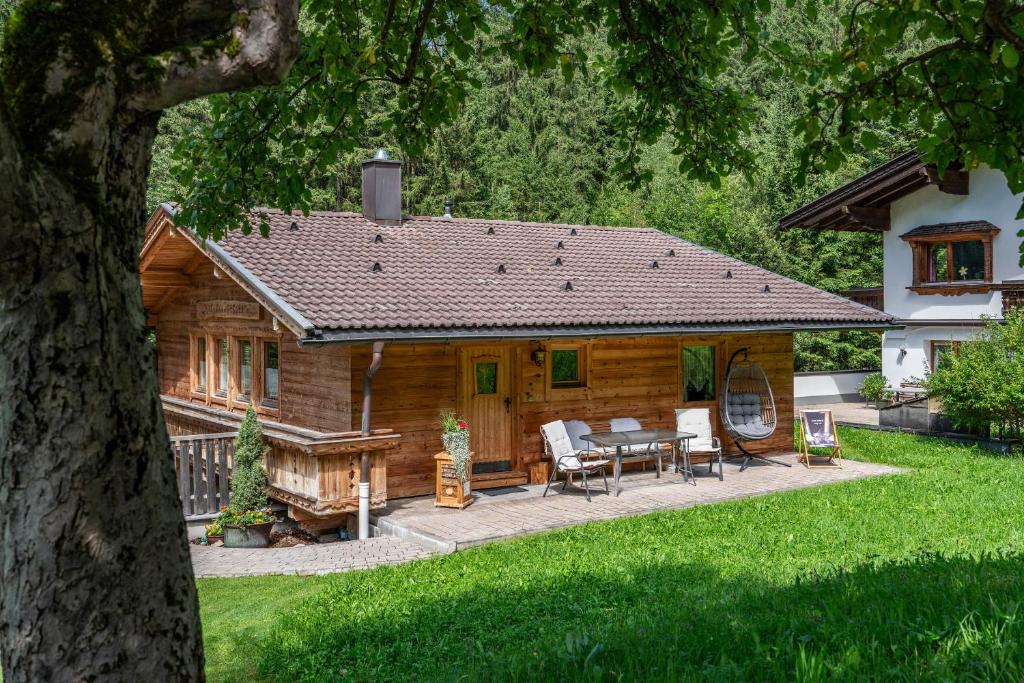 um chalé de madeira com uma mesa e cadeiras no quintal em Holzknechthütte em Mayrhofen