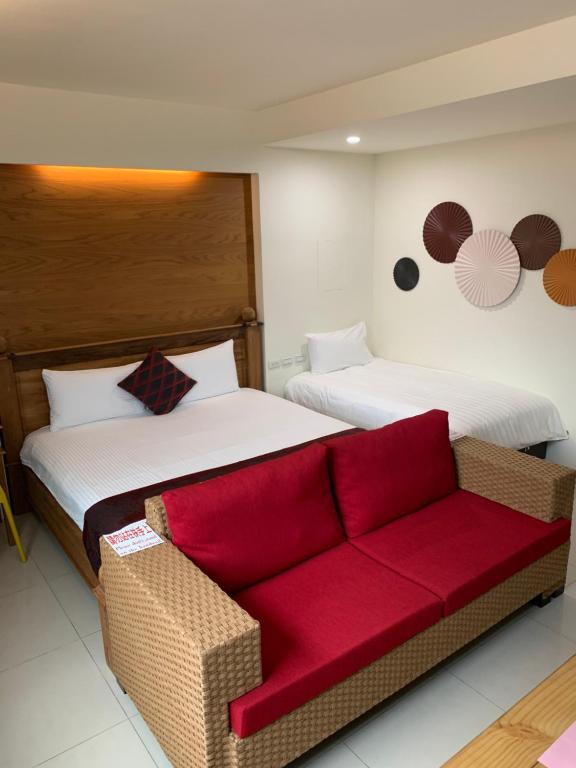a hotel room with two beds and a red couch at 開心居-正市中心電梯民宿-步行東大夜市5分鐘 in Hualien City