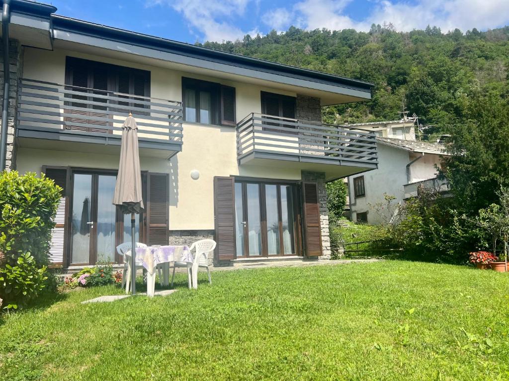 a house with a table and an umbrella in the yard at Villa Moroni in Sondrio