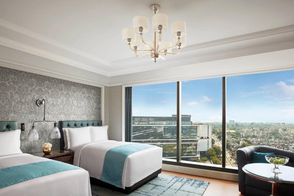 a bedroom with two beds and a large window at The Ritz-Carlton, Pune in Pune