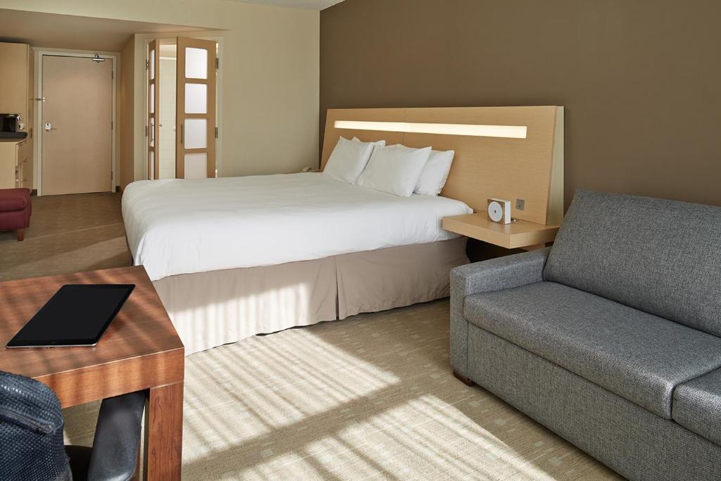 une chambre d'hôtel avec un lit et un canapé dans l'établissement Novotel Montréal Aéroport, à Dorval