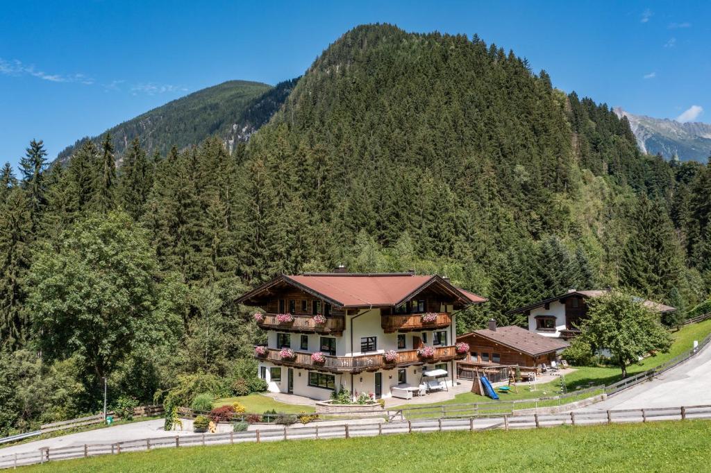 a large house on a hill with a mountain at Landhaus Ifangl in Mayrhofen