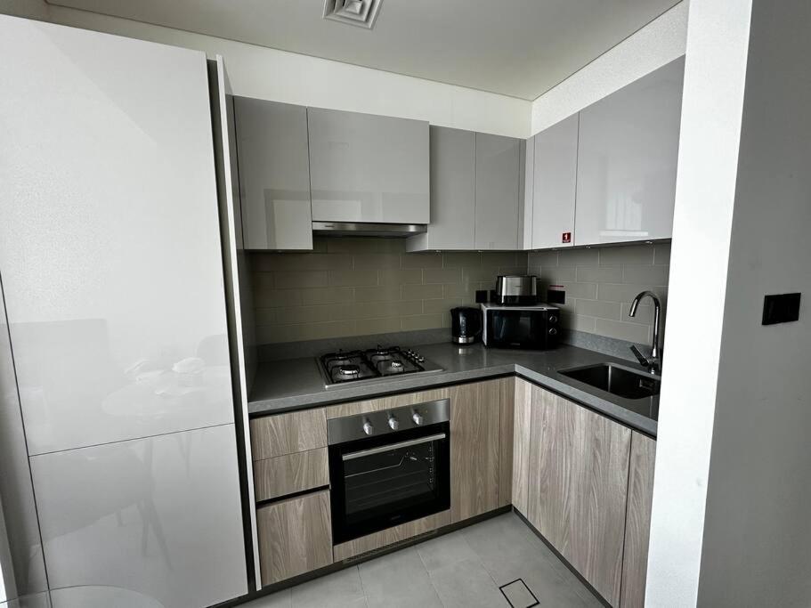 a kitchen with white cabinets and a stove top oven at Cosy 1 bedroom Burj Khalifa view in Dubai