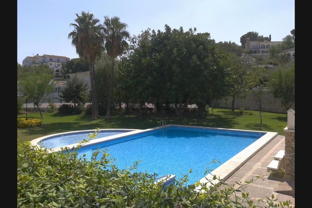 una grande piscina blu in un cortile alberato di Apartamento en el casco antiguo. ad Altea