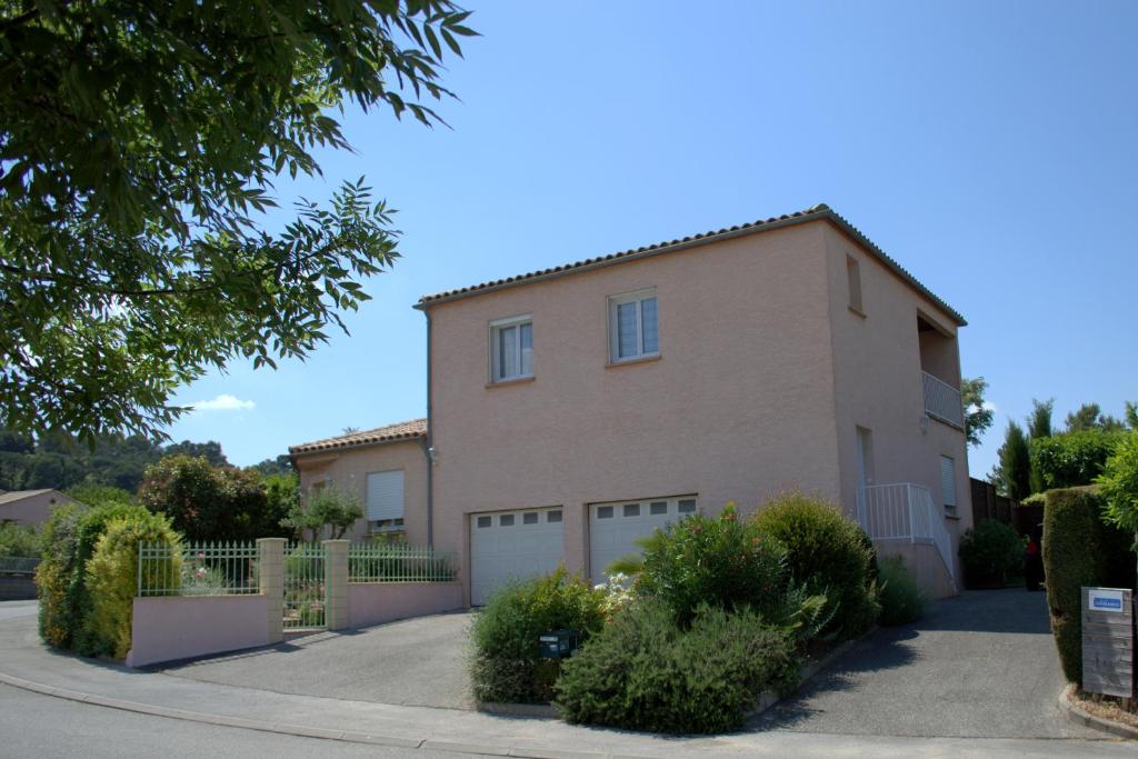 a large brick house with a fence and bushes at Gîte L'Orée du Lac in Carcassonne