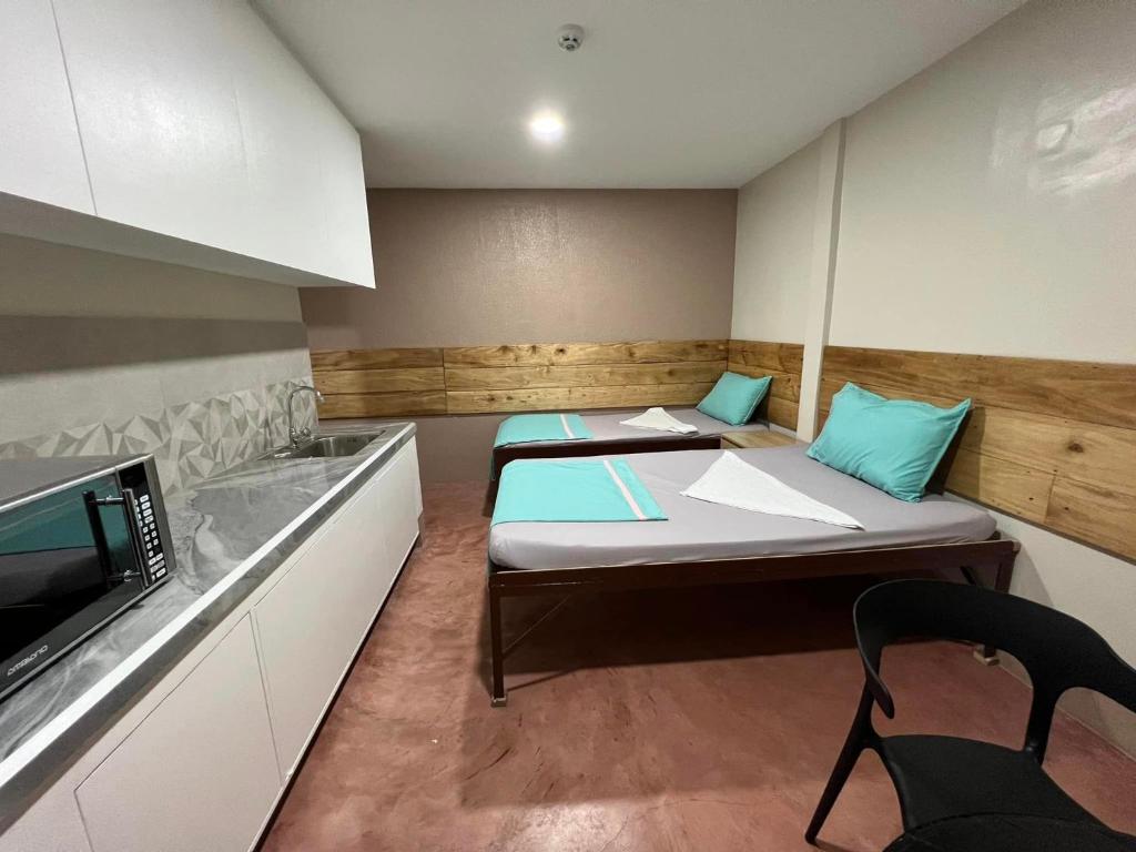 Kleines Zimmer mit 2 Betten und einer Mikrowelle in der Unterkunft Maila's Lodging House in Casisang