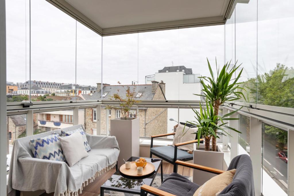 Elle comprend un balcon doté d'un mobilier blanc et de grandes fenêtres. dans l'établissement L'Air - Elégant 2 chambres avec loggia dans résidence de haut standing, à Rennes