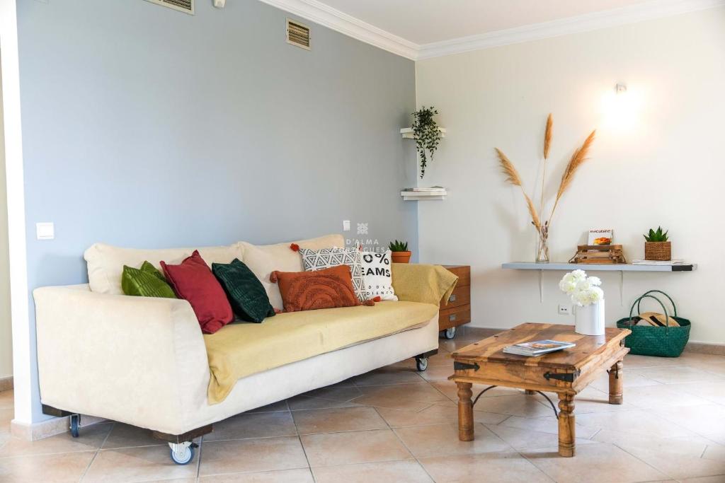 a living room with a white couch with colorful pillows at Apartamento Tocano Beach - By Dalma Portuguesa in Albufeira