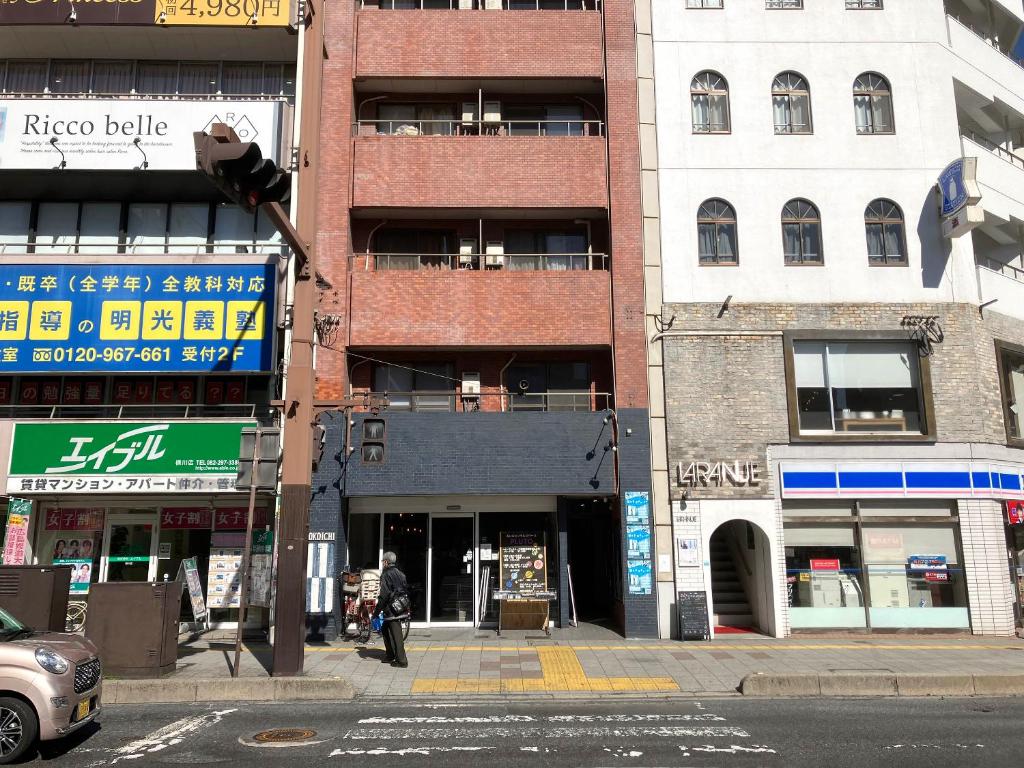 un hombre caminando por una calle frente a los edificios en Casa Viento Stay Inn, en Hiroshima