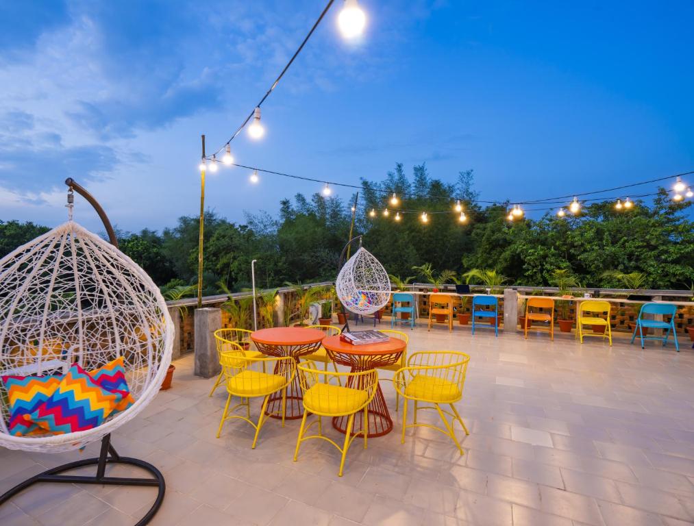 un patio con mesa, sillas y luces en goSTOPS Pondicherry, Auroville en Auroville