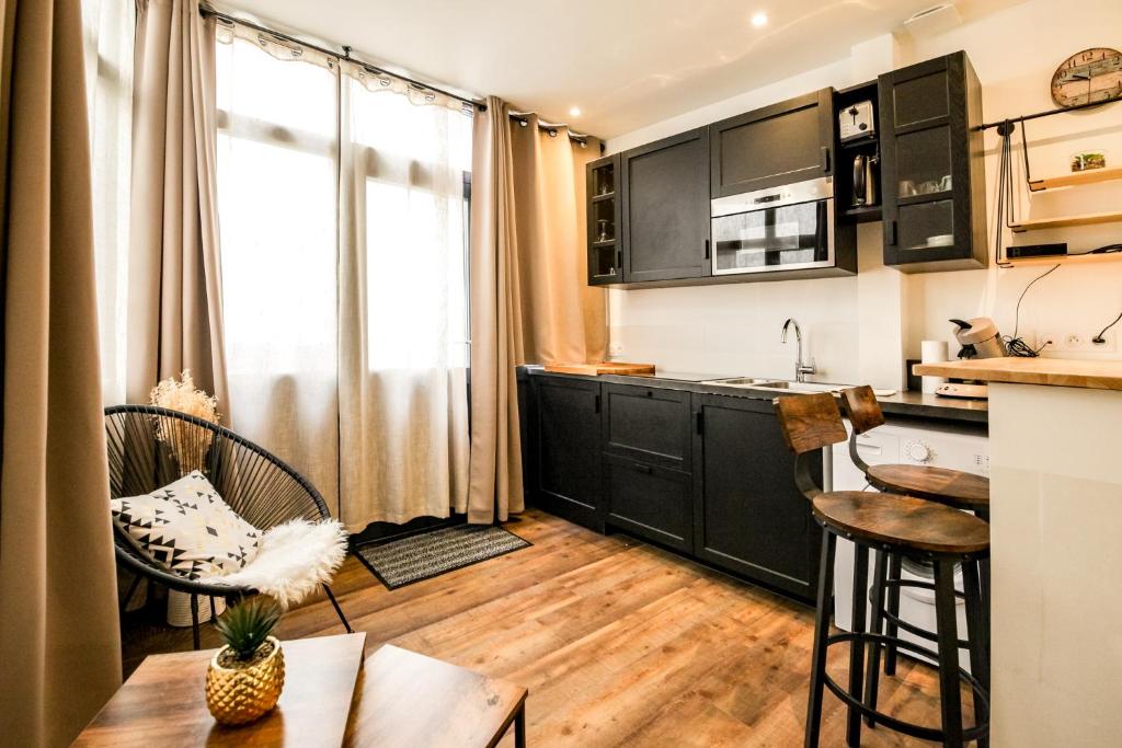 eine Küche mit schwarzen Schränken sowie einem Tisch und Stühlen in der Unterkunft L'Hermine - Coquet - Port - Linge inclu in Vannes