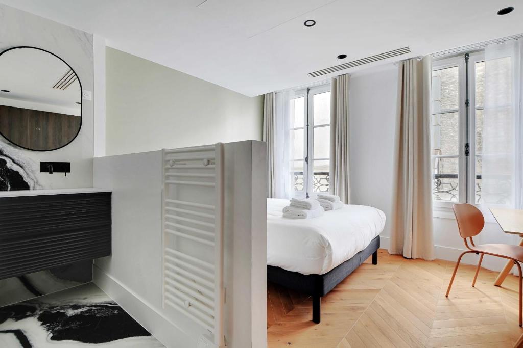 a white bedroom with a bed and a table and chair at Spacious &amp; Modern Home in Central Paris - 3BR8P - A40 in Paris