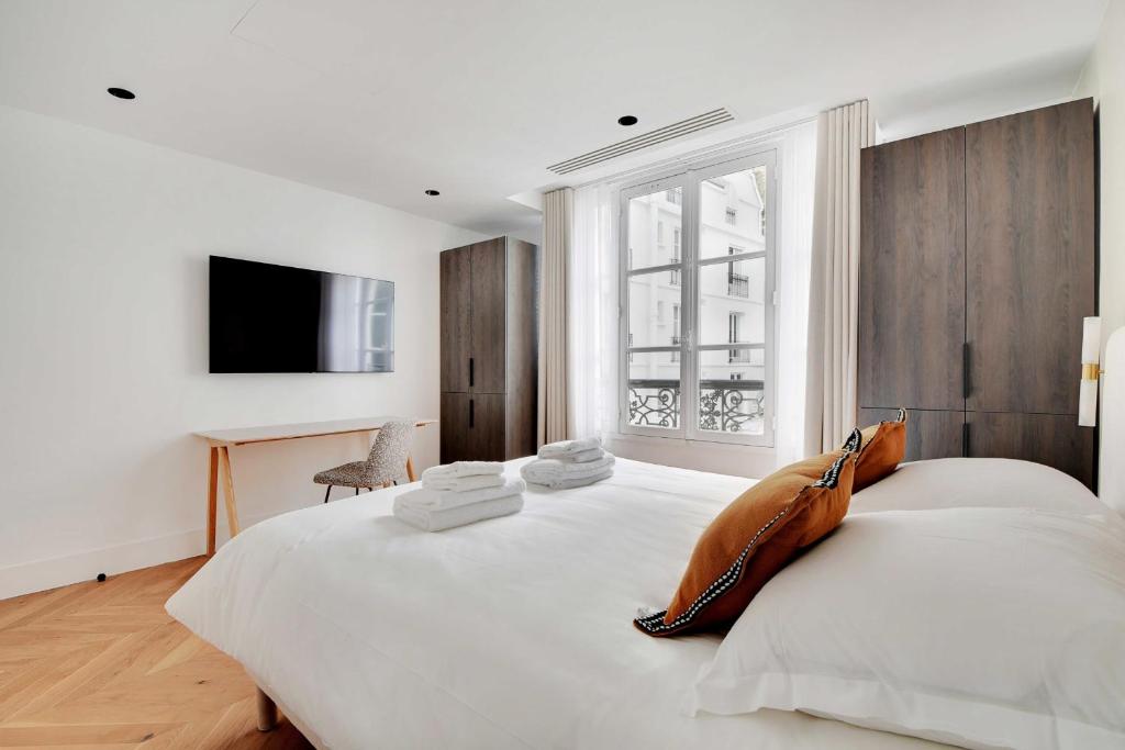 a white bedroom with a large bed with a purse on it at Spacious &amp; Modern Home in Central Paris - 3BR8P - A40 in Paris