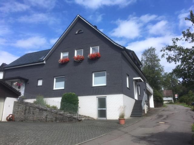 a black and white house with red flower boxes at Schöne Ferienwohnung Nähe Biggesee 