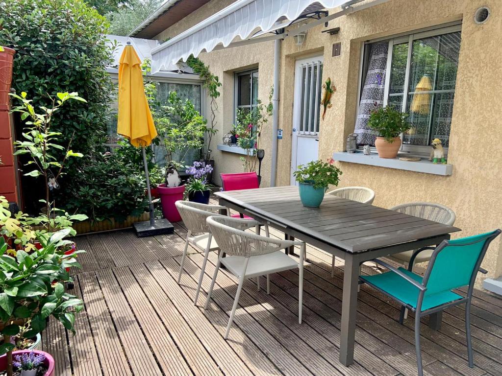 eine Terrasse mit einem Holztisch, Stühlen und einem Sonnenschirm in der Unterkunft Chambre salle de bain privée à 20 minutes de Paris in Fontenay-sous-Bois