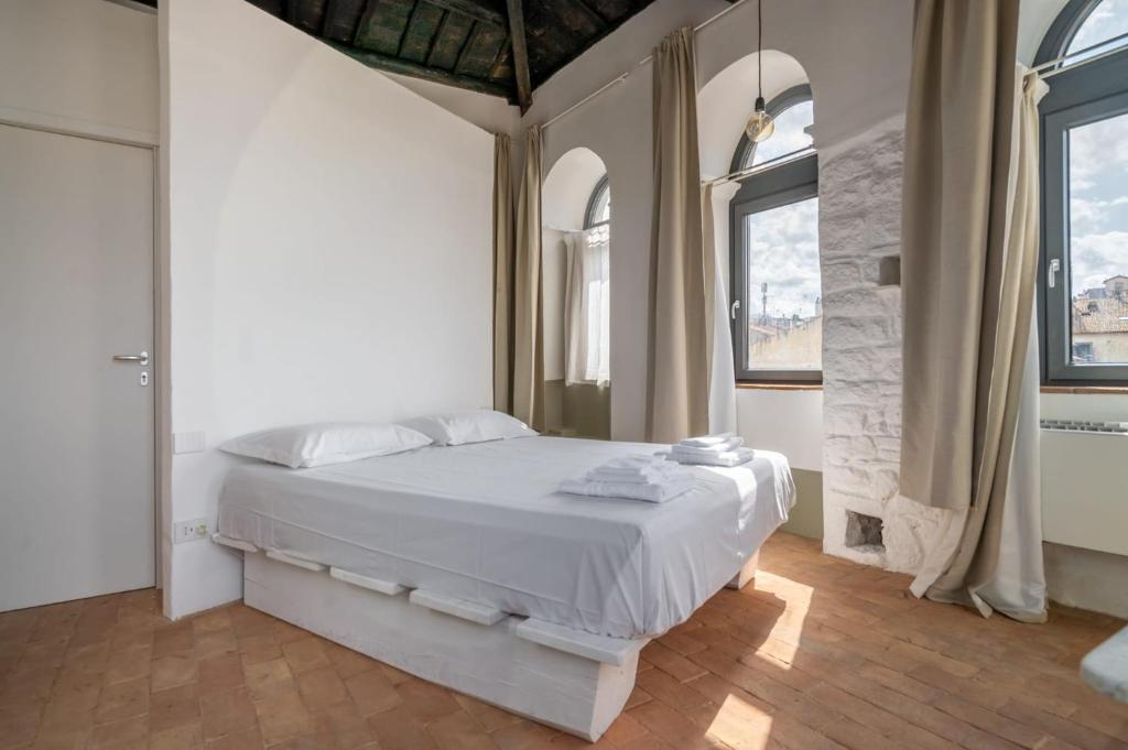 a bedroom with a white bed and two windows at Torre Subrosa, vasca in camera cromoterapia in Viterbo