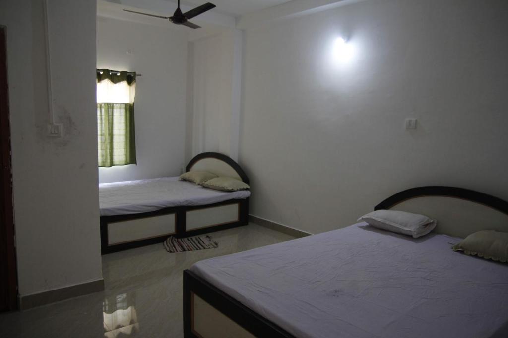 ボルプルにあるGeetanjaliのベッド2台と窓が備わる客室です。