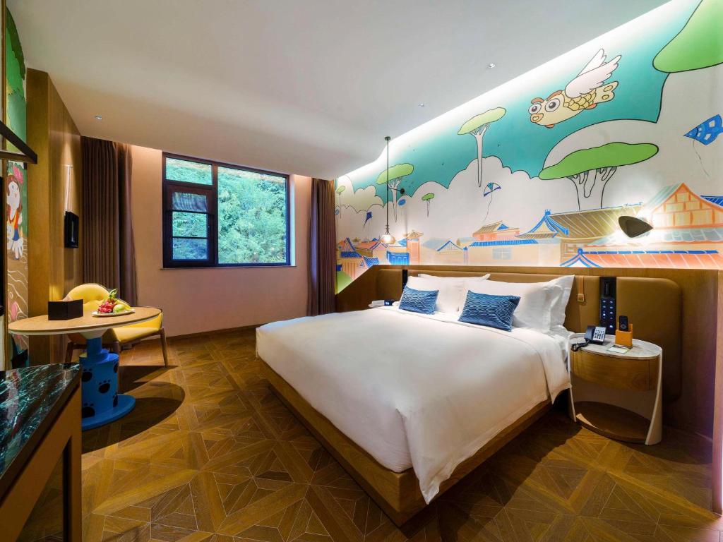 ein Schlafzimmer mit einem großen Bett und einem Gemälde an der Wand in der Unterkunft Novotel Linfen Mount Yun in Xiangning